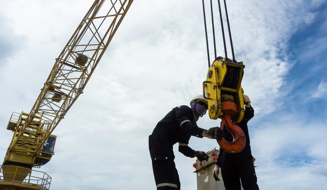 A mechanical engineer and another crew member are inspecting a piece of the rigging for a crane system.
